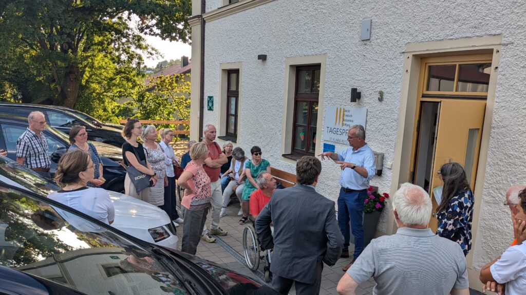 Die Gruppe steht vor der ehemaligen Schule und hört Georg Sigl-Lehner zu