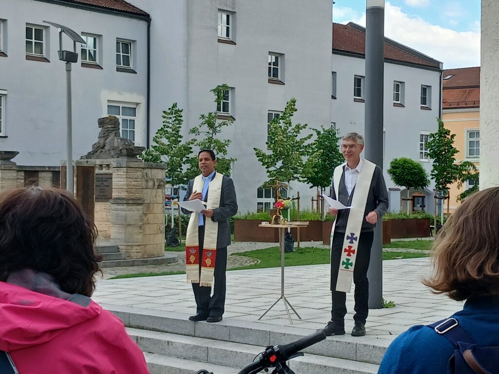 Pfarrer Christian Muschler und Pfarrvikar Biju Varghese stehen auf den Stufen der Kirche St. Marien und sprechen die Fahrradsegnung im Rahmen des Stadtradeln